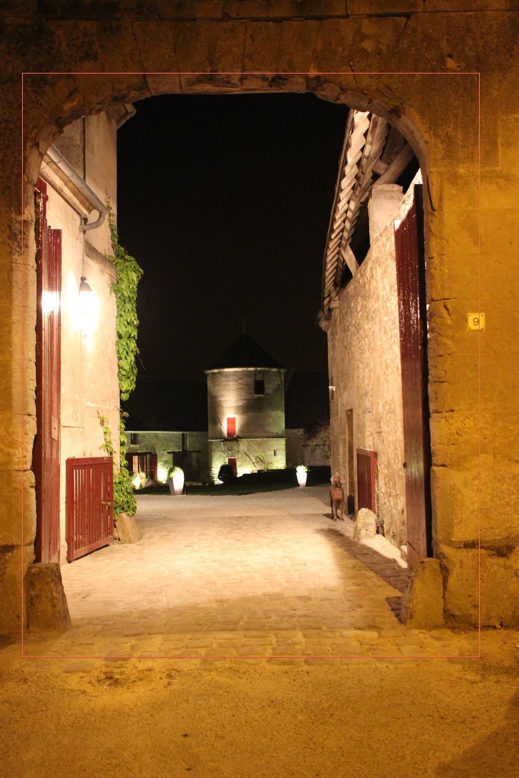 Le porche la nuit, le pigeonnier éclairé au fond de la cour